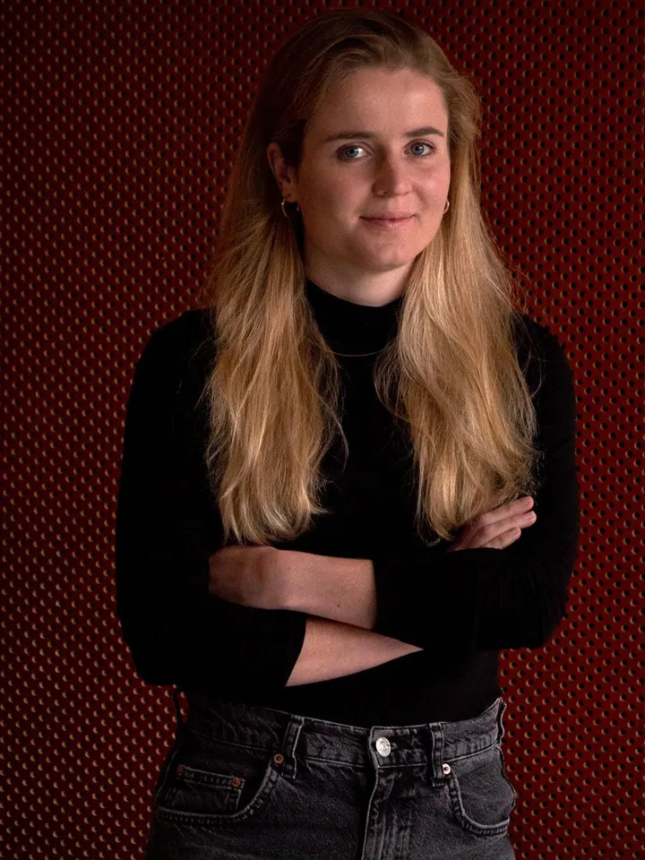 Ellie Keel, Producer. Headshot. White woman in a black long sleeved top with long blonde hair