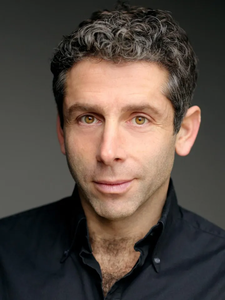 Elliot Levey headshot - black shirt, with dark background