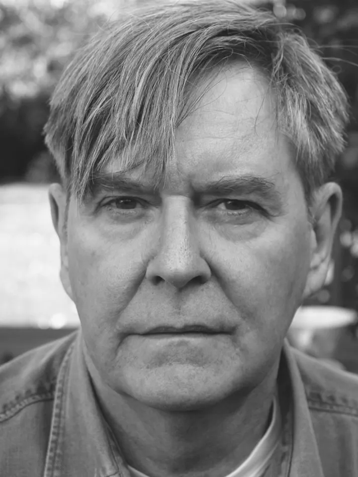 Black and white headshot of James Fleet, white man with brown hair.